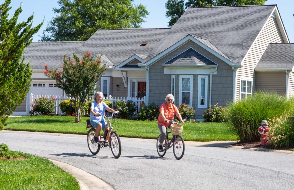Two Senior Women Riding Bikes Outside, Smiling