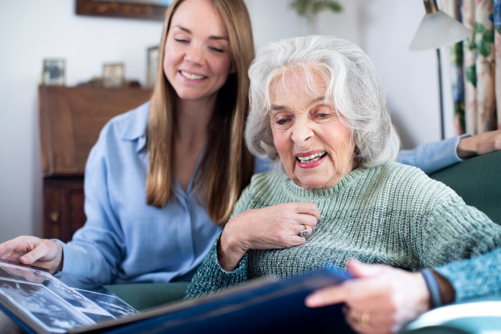 Caregiver Reading to Senior Woman, Smiling