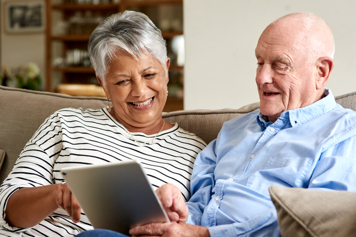 Senior Man and Woman Looking at Tablet Smiling
