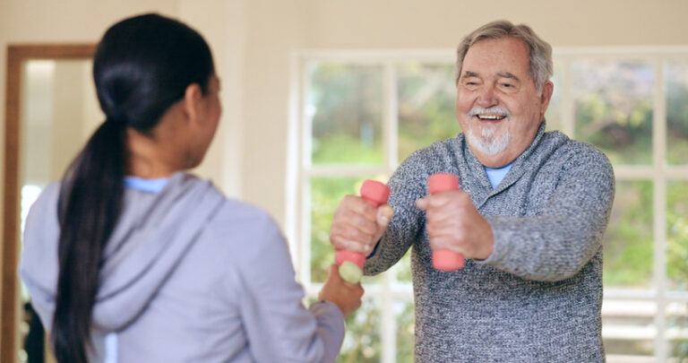 Phyiscal Therapist Working with Senior Man Lifting Small Weights